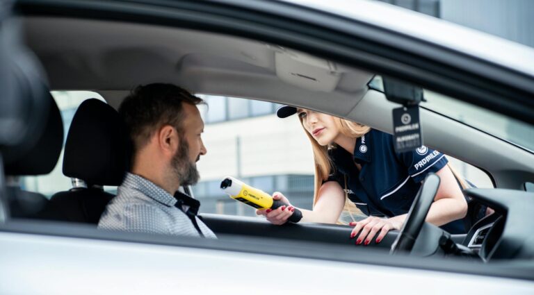 A police officer conducts a breathalyzer test on a male driver during a road safety check.